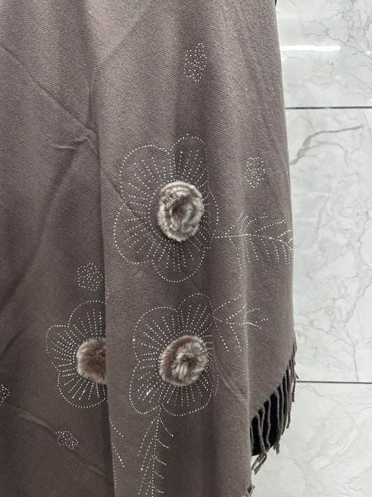 The mix of the earthy taupe tone with those tactile faux-fur accents and delicate stonework gives off a very "refined cozy" vibe.