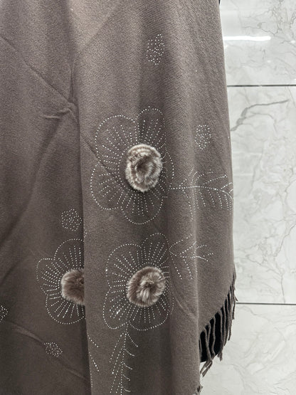 The mix of the earthy taupe tone with those tactile faux-fur accents and delicate stonework gives off a very "refined cozy" vibe.